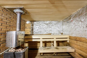 cozy sauna with wooden benches, brick wall, and a metal stove. The walls are partially covered with...