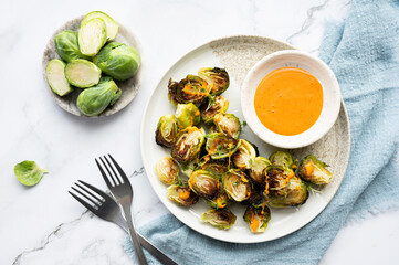 Caramelized Brussels sprouts with dip sauce, next to raw halved sprouts.