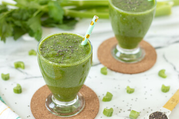 Green celery smoothie with chia seeds on white kitchen table. Healthy vegan detox blended drink.