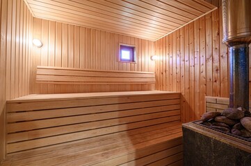 bright sauna room featuring wooden benches, walls, and ceiling, illuminated by two wall lights....