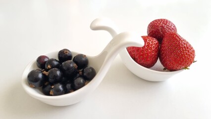 fresh and healthy strawberries. White curved ceramic fruit vase containing red strawberries and blackberries. Mixed berries in white fruit bowls. Healthy eating concept. Macro 