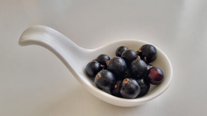 White curved ceramic fruit vase, containing blackcurrants, healthy eating concept. Top view.
