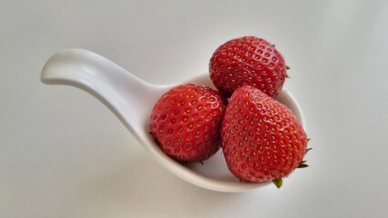 strawberries in a bowl. White curved ceramic fruit vase containing red strawberries, healthy eating...