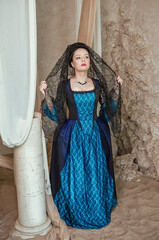 Beautiful young woman wearing medieval dress stands among ancient ruin
