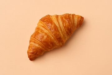 Fresh croissant against a pastel peach background stock photo