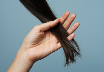 A caucasian woman holding a large lock of her dark brown hair. Hair health and beauty concept for hair care product marketing.
