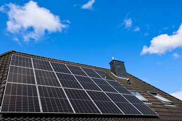 Photovoltaic panels providing green energy on a roof under blue sky