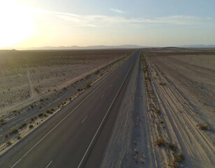 Fototapeta premium Highway stretching through desert landscape at sunset