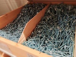different types of screws stored in organized bins in a hardware store aisle. Screws organized...