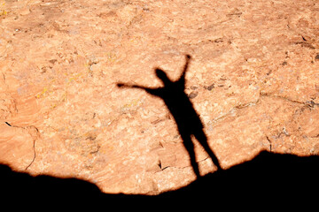 Woman Hiking Shadow Cast onto Red Sandstone Rock from Bright Sun