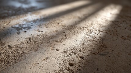 Sunlight creating shadows on textured concrete surface with water puddle