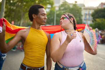Young couple holding rainbow flag celebrating pride festival