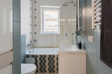 Bathroom interior design in a real estate property or rental apartment. A small, compact home room with a bath, shower, sink, and toilet for hygiene and home improvement ideas.