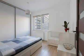 Parents bedroom interior with a baby crib for co-sleeping in a modern apartment. Home furniture for a family with a newborn, creating a nursery space in a residential room for a new life.