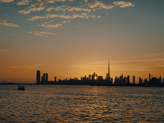 Obraz premium Golden hour over Dubai cityscape, with the sun setting behind downtown skyscrapers , reflection in the water