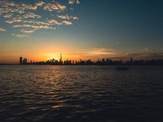 Orange evening sun silhouettes the city skyline over the water