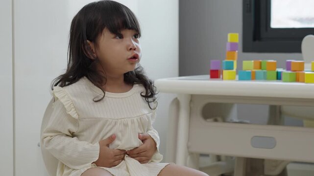 toddler gir learning sit on toilet wc seat at home. child being potty trained and suffering from stomachache and constipation