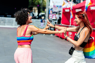 Two women holding hands and dancing at pride parade celebrating love and inclusivity