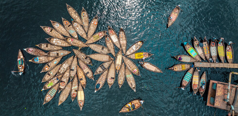 Aerial view of wooden boats clustered on the rippling water, creating a captivating mosaic of textures and tones, Dhaka, Dhaka District, Bangladesh.