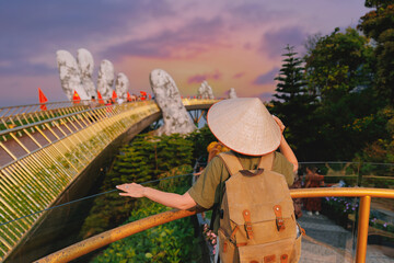 Scenic view of ba na hills with female tourist on golden bridge at sunset, Da nang, Vietnam