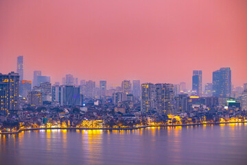 Hanoi vibrant skyline at sunset with lights reflecting on water, panorama aerial view