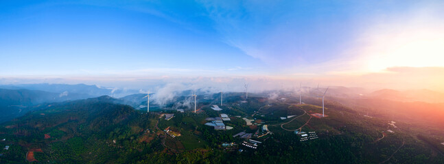 Fototapeta premium Wind generators with clouds in mountains, industry landscape. Aerial view Turbines for eco renewable electric power production banner