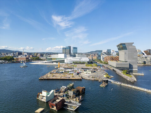 Aerial view of the Oslo Opera House and the Munch Museum gleaming under the bright sky, with waterfront structures adding contrast, Oslo, Norway.