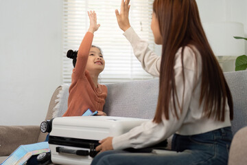 Travel Excitement. A mother and daughter sharing a high-five while preparing for their trip.