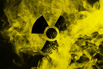 Radioactive sign and yellow toxic smoke against black background
