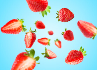 Yummy fresh strawberries swirling in air against light blue background