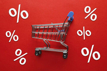 Hot sale, special offer. Percent signs and shopping cart on red background, top view