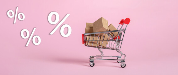 Hot sale, special offer. Percent signs flying near shopping cart with boxes against pink background
