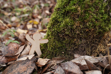 Wooden figure explores nature in a woodland setting surrounded by autumn leaves
