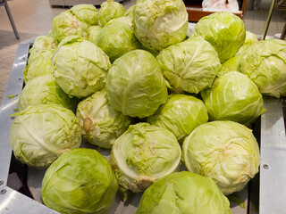Fresh green cabbages piled at a local market during a sunny afternoon