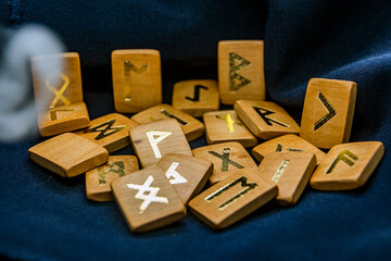 Wooden runes on a black background with an impending gray smoke ring	
