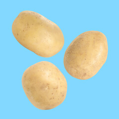 Three raw potatoes flying against light blue background