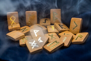 Wooden runes on a black background shrouded in smoke	

