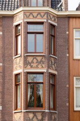 Obraz premium Historic brick building features decorative windows in an urban setting during daylight, showcasing architectural details and craftsmanship