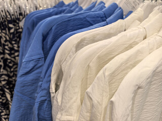 Soft cotton shirts in shades of blue and white hanging in a boutique store