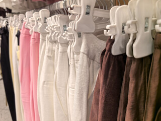 Colorful collection of stylish trousers hanging on display in clothing store