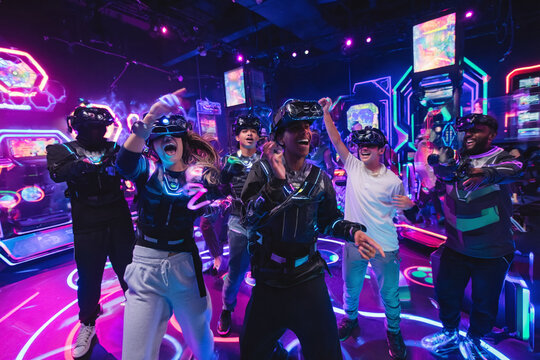 Immerse yourself in a world of vibrant fun with this group enjoying virtual reality gaming. Neon lights happy expressions convey excitement and futuristic entertainment.