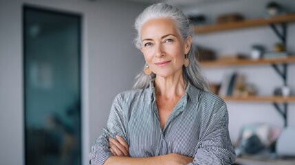 Smiling confident stylish mature middle aged woman standing at home office. Old senior businesswoman, 60s gray-haired lady executive business leader manager looking at camera arms crossed, portrait.,