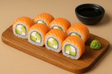 Fresh salmon sushi rolls with avocado and cream cheese on wooden board. Served with wasabi and soy sauce in small black bowl. Concept of Japanese cuisine and healthy food