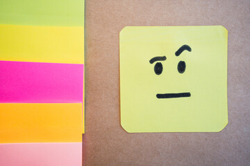 Angry face drawn on colored paper with black marker with a solid uniform background