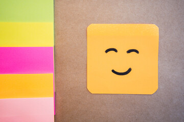 Happy face drawn on colored paper with black marker with a uniform solid background