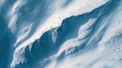 Aerial view of snowy mountain slopes with sharp ridges and natural patterns ideal for winter sports ads, nature documentaries and high-altitude landscape visuals