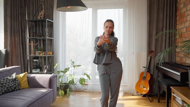 Woman practices a dance routine at home from an online tutorial on her tablet. She uses her phone to record for self-analysis or to get live feedback from a remote instructor during a virtual lesson.