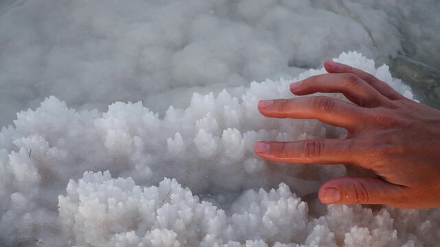 Touching the white salty crystals on the selenium sea with your finger and hand