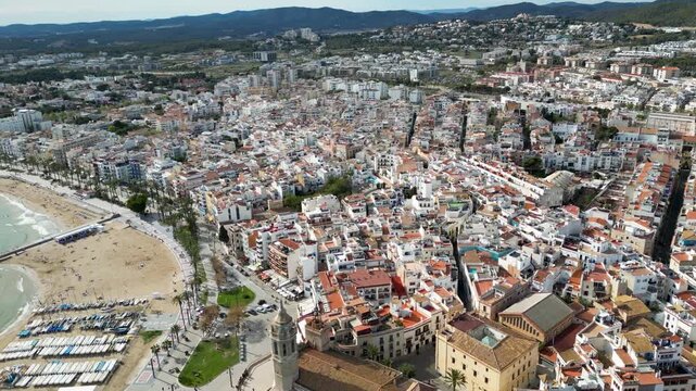 Aerial view of buildings with red rooftops and narrow streets contrasting with the blue sky, showcasing urban planning and architecture, Sitges, Barcelona, Spain.