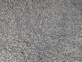 Textured gravel surface showcasing diverse stone sizes in a tranquil outdoor setting during daytime